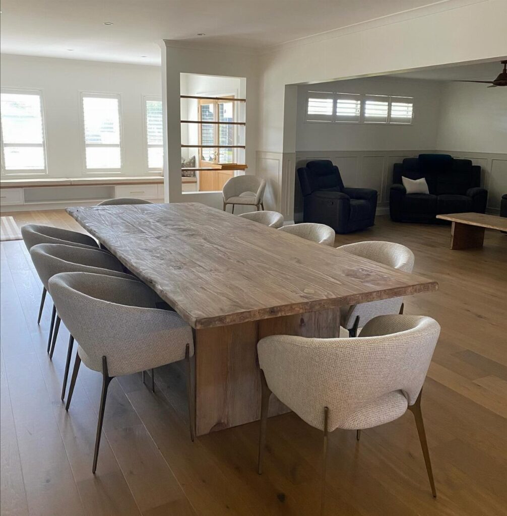 Long wooden dining table with matching light grey upholstered chairs in a bright room