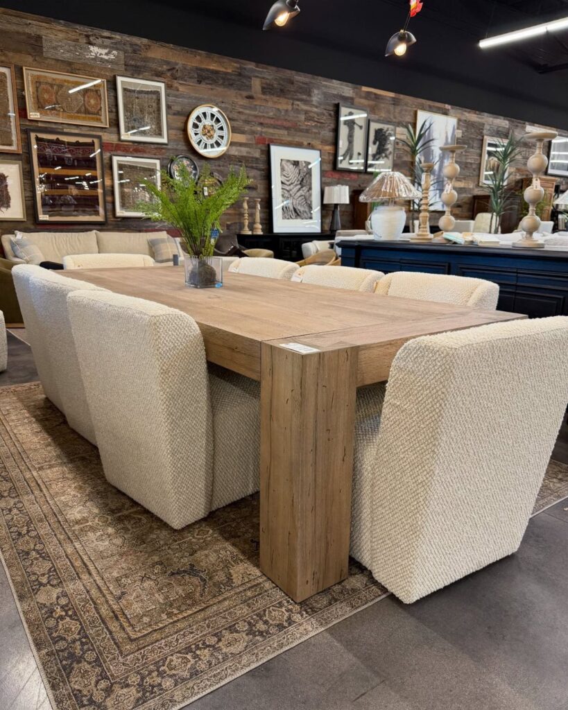 Large light-wood dining table with cream upholstered chairs on a patterned area rug