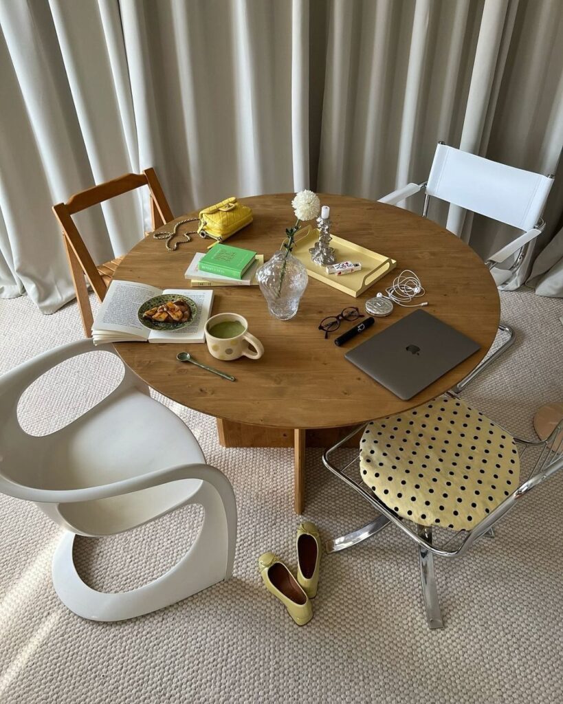 Round wooden table surrounded by four mismatched chairs in a bright room.