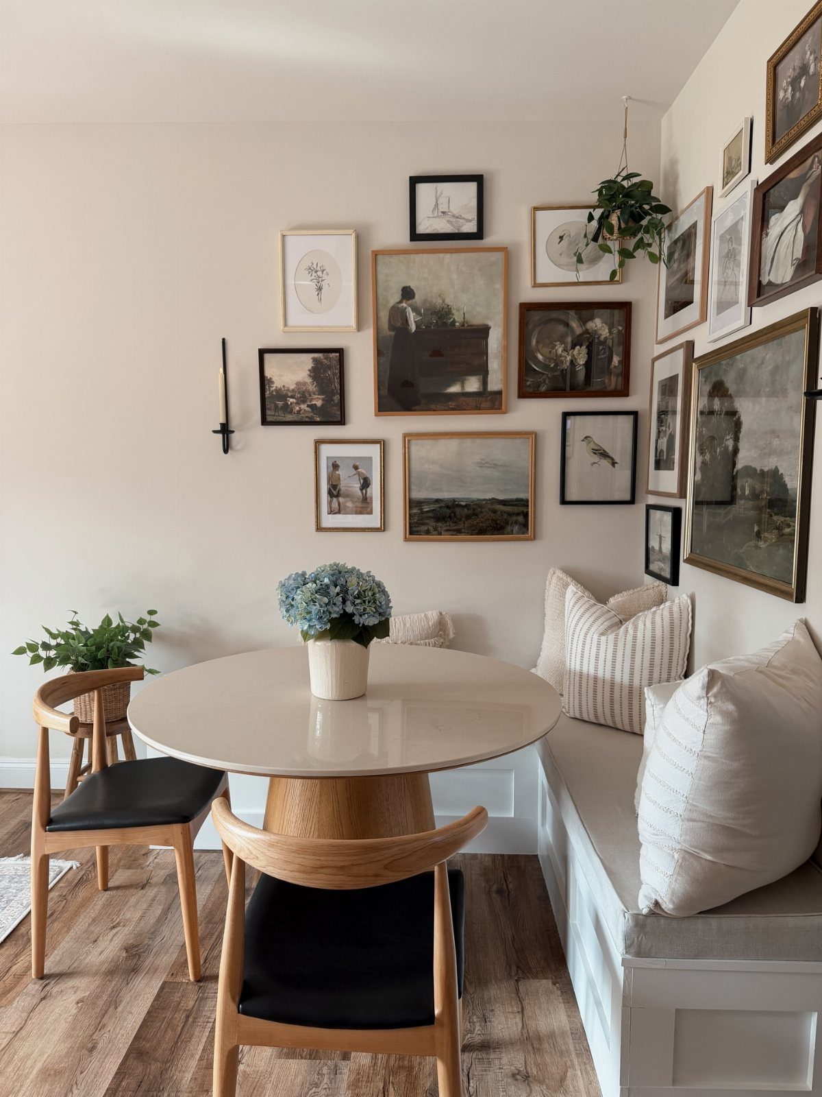 Round white dining table with corner banquet seating and a gallery wall of art.