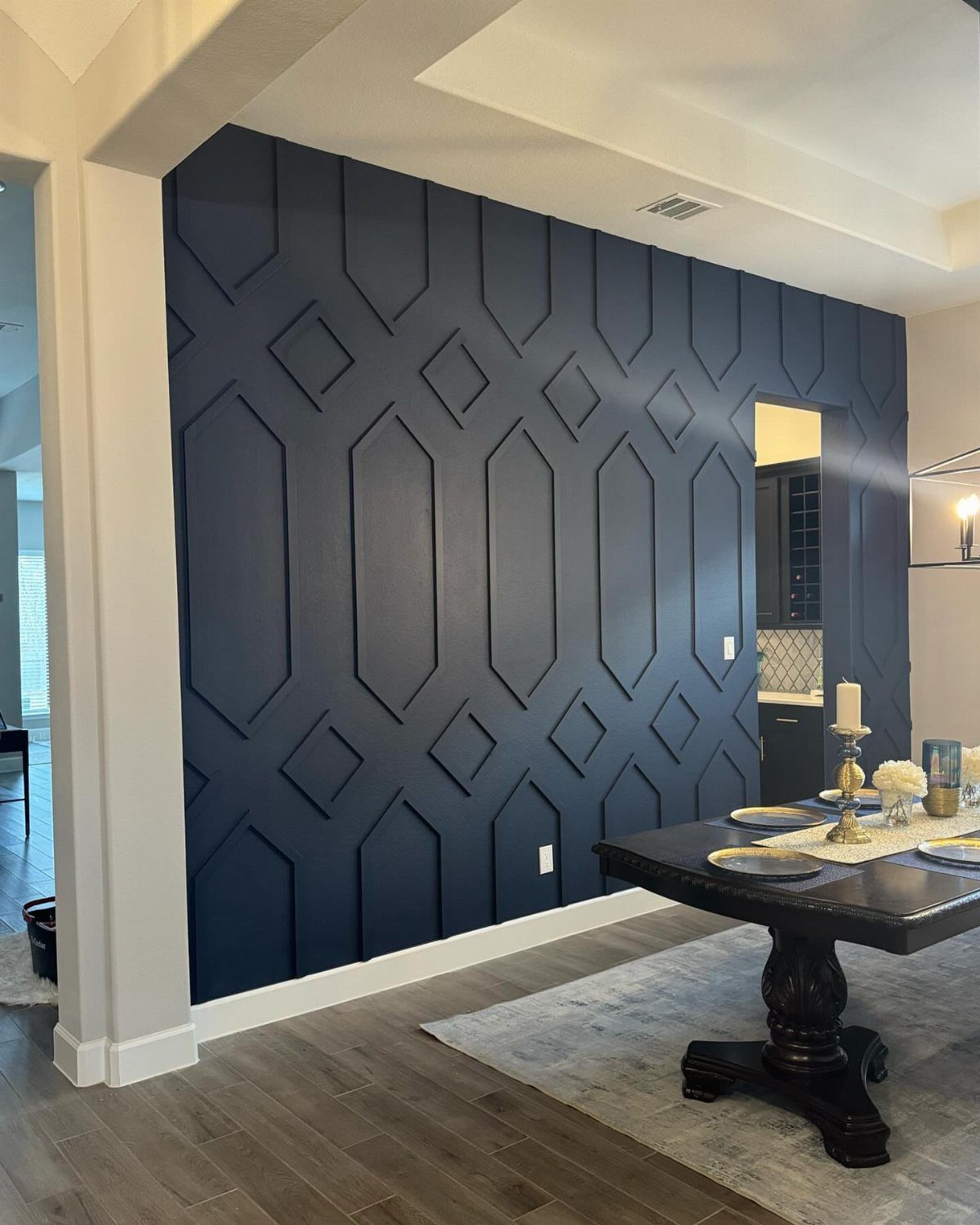 Dark blue geometric accent wall in a dining room with a wooden table.