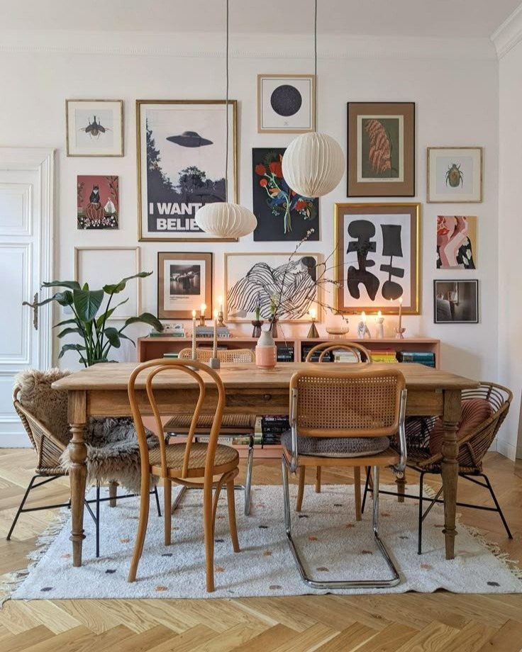Dining room with a wooden table and a gallery wall of framed art prints.