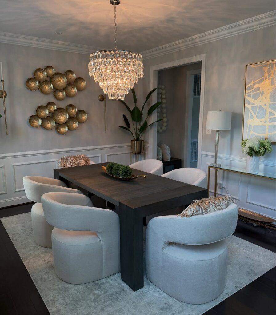Dark wooden dining table with a gold centerpiece bowl and white curved chairs.