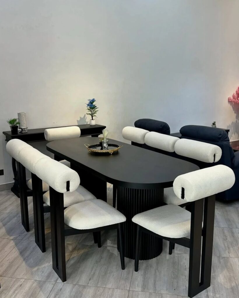 Oval dark brown dining table with white upholstered chairs in a minimalist room.