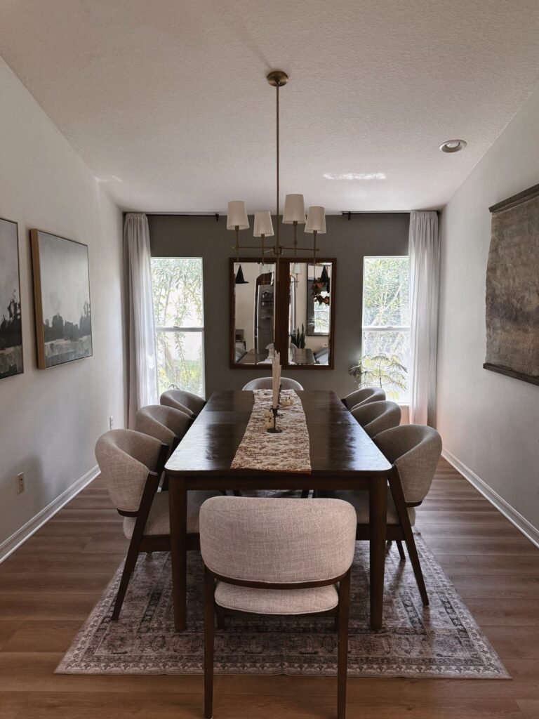 Dining room with a dark wood table and grey chairs on a patterned rug.
