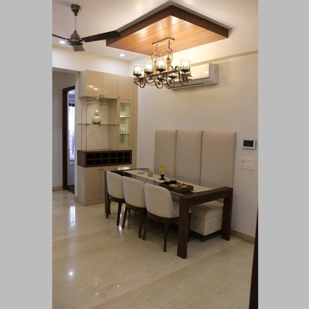 Rectangular wooden dining table with a white upholstered bench seat against a wall.