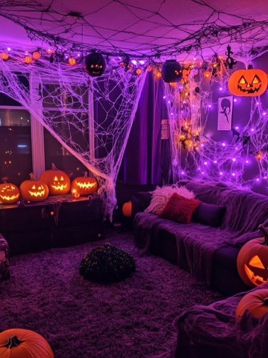 Halloween decorated living room with purple lights, spider webs, and glowing carved pumpkins.
