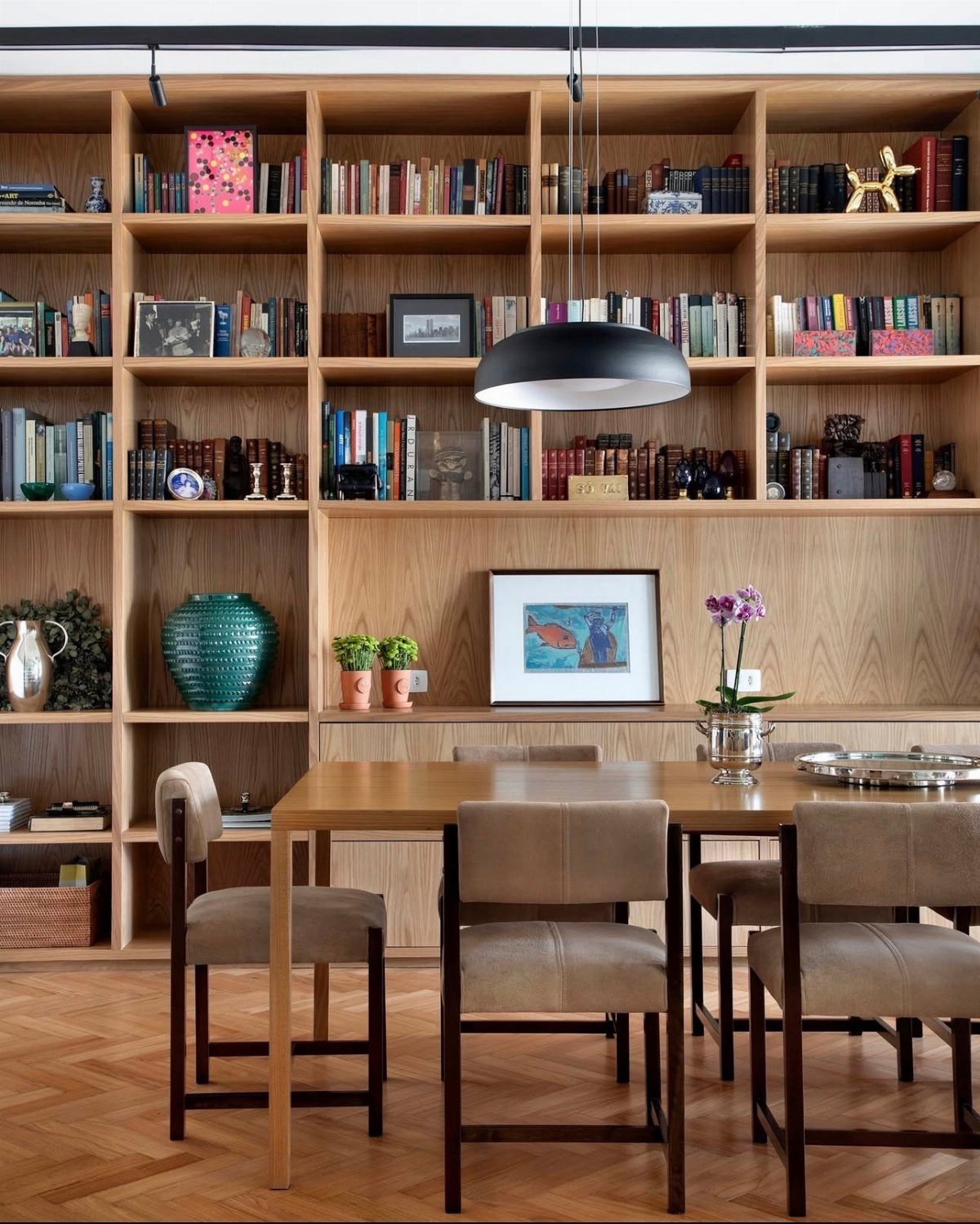 Light wood built-in bookcases filled with books behind a wooden dining table and chairs.