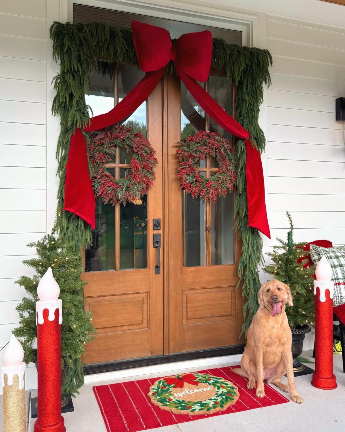 Wooden double doors decorated with green garlands, red bows, and festive wreaths.