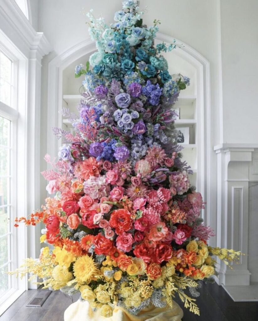 Rainbow floral Christmas tree in a bright white modern living room setting.