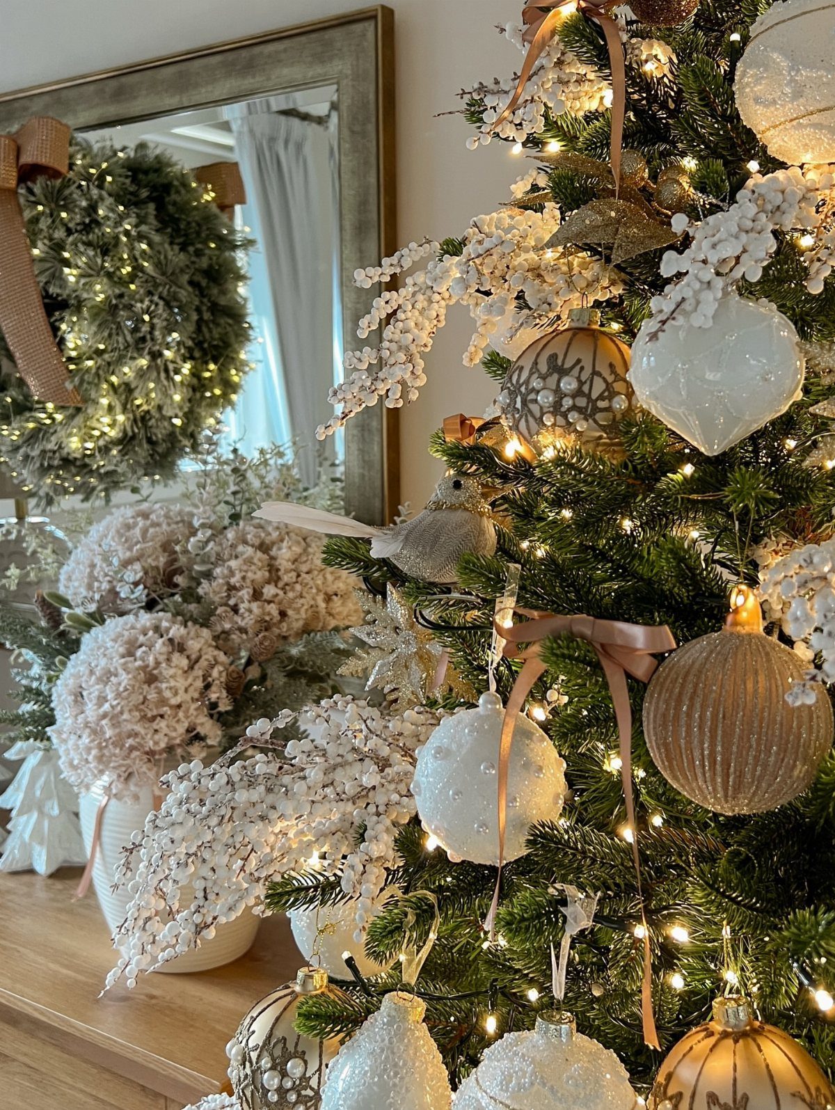 Christmas tree decorated with neutral white and gold ornaments and beige ribbons