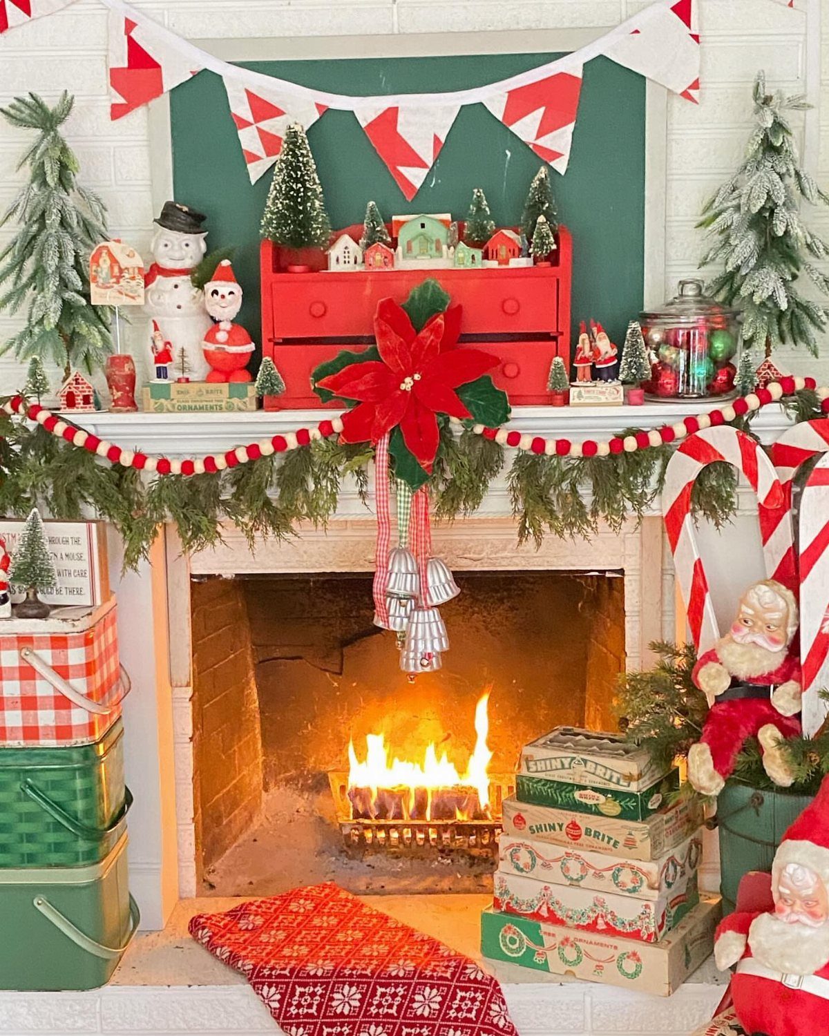 Christmas mantel decorated with a red and white theme, garlands, and miniature figurines.