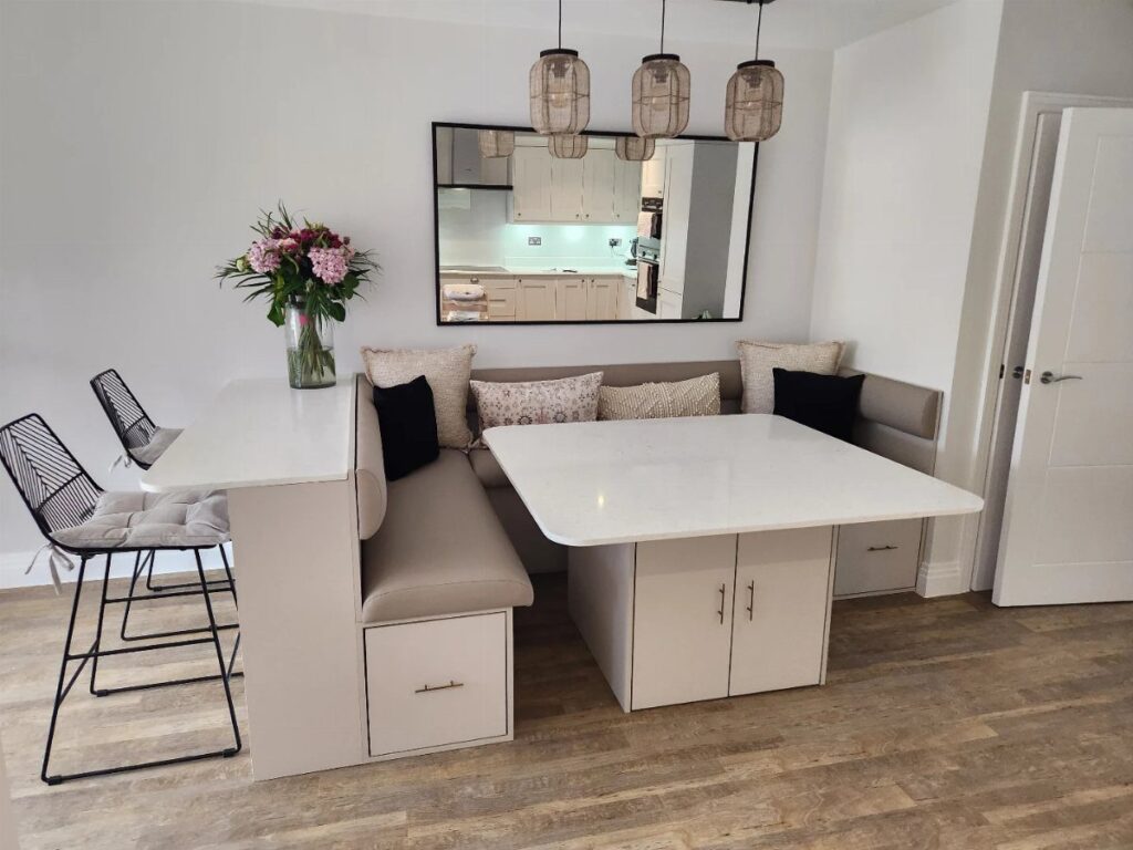 L-shaped beige built-in banquet seating with a white dining table and wall mirror.