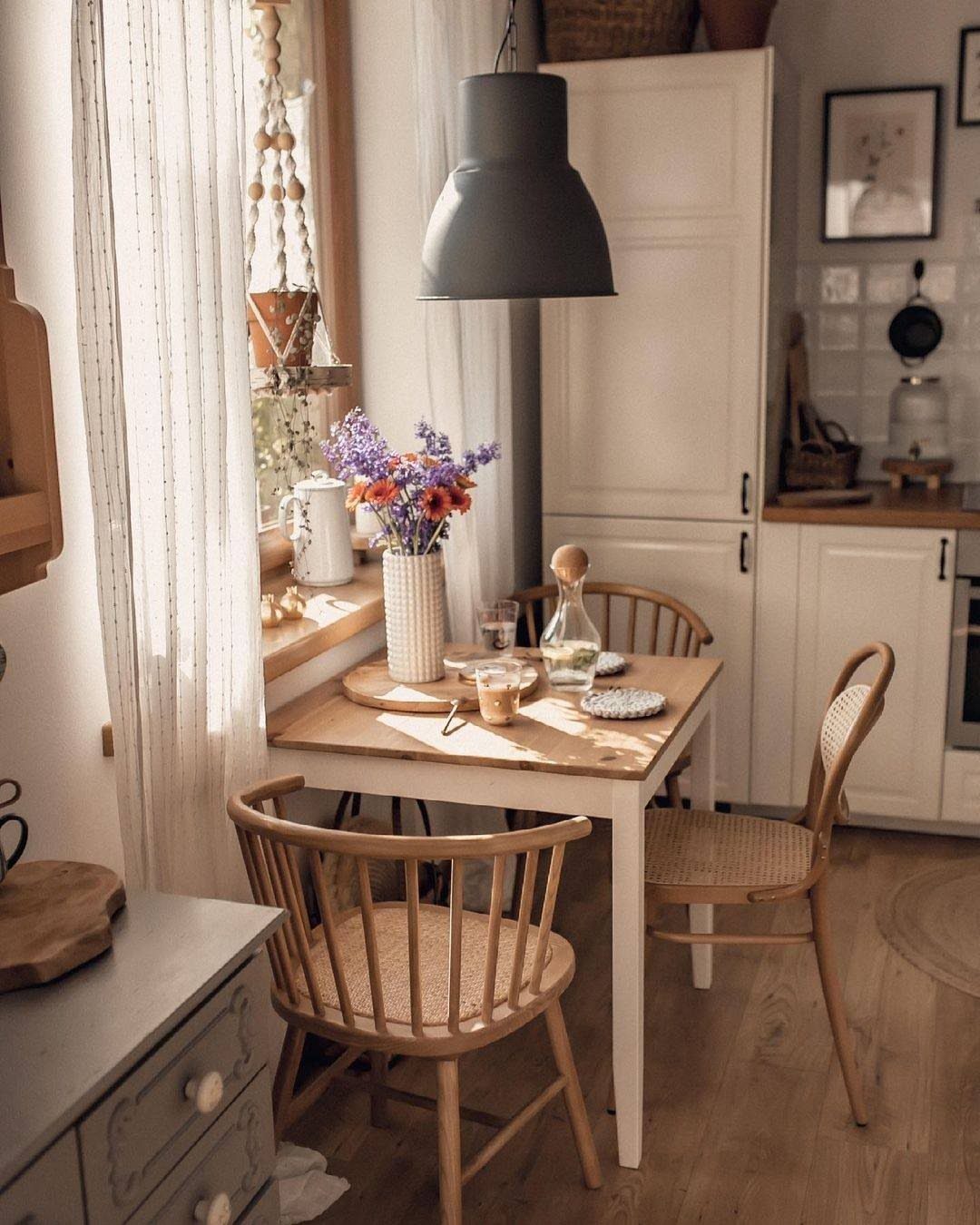 Small rectangular wooden dining table with two woven chairs in a bright kitchen.