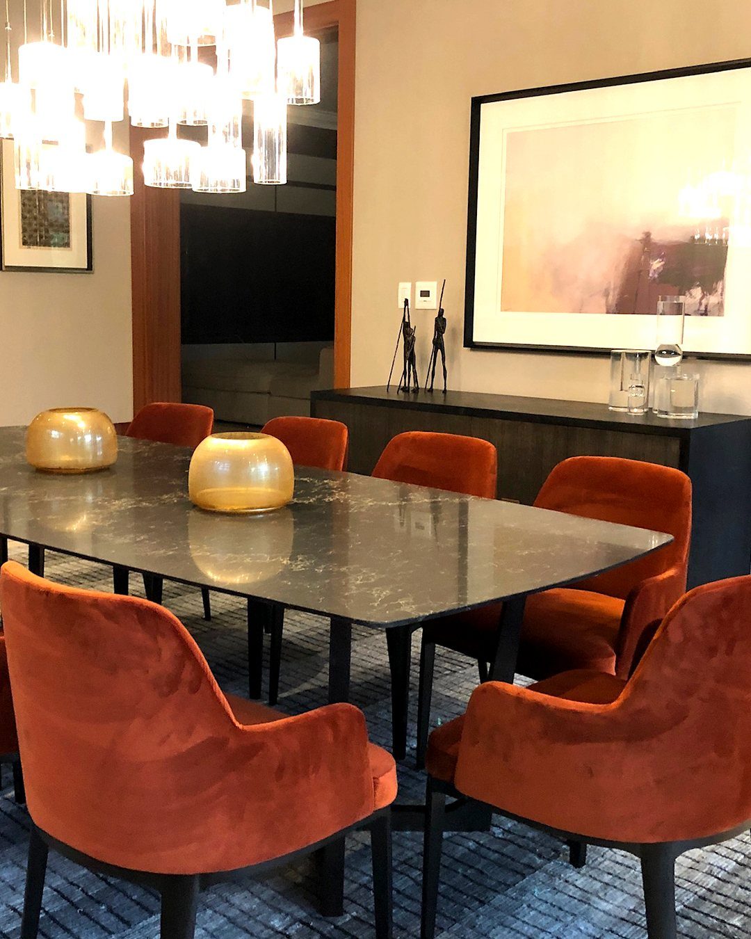 Dining room with burnt orange velvet chairs and a dark stone table.