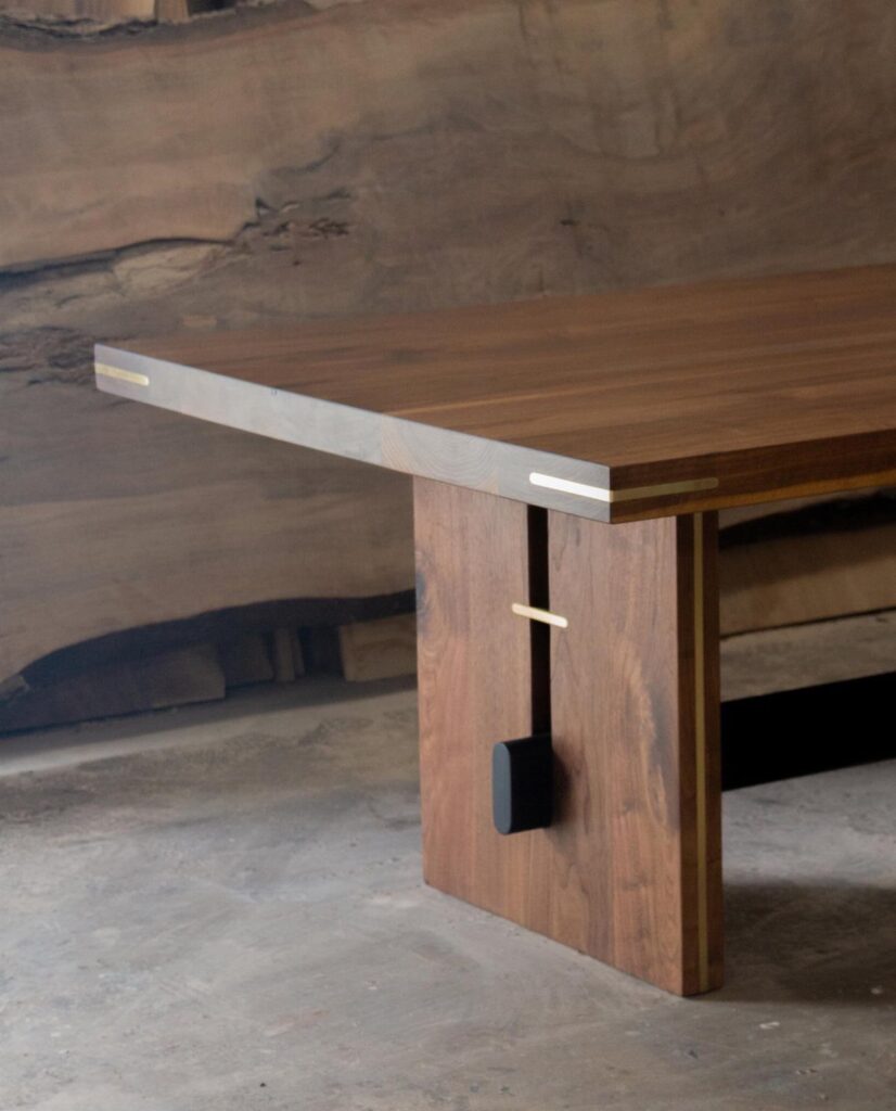 Walnut wood dining table with gold metal inlays and a solid wood leg.